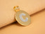 Solid 18 K gold Celestia initial disc pendant with pavé white-gold “C” resting on beige fabric—red-carpet style like Taylor Swift.