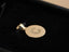 Solid 18 K gold Celestia disc pendant resting on black velvet; brushed “C” engraving and high polish evoke Taylor Swift red-carpet elegance.