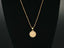 Celestia disc pendant on fine gold chain displayed on black velvet bust; sleek red-carpet layering inspired by Taylor Swift.
