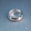 Modern 18k white gold wedding band on a textured background.