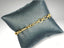 Elegant 18k gold bracelet on dark gray cushion showcasing art gold jewelry craftsmanship