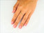 Hand with pink nails wearing an 18k yellow gold square shape ring, showcasing minimalist luxury