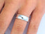 Elegant White 18k Gold Wedding Band on finger, showcasing sleek design and polished finish.