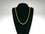 Elegant 18k gold rope chain necklace on a black velvet jewelry stand
