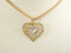 Gold double heart pendant with filigree design and diamond accents on a chain necklace