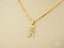 Gold pendant necklace in 18k yellow gold with stick figure charm and blue gemstones