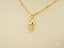 Gold pendant necklace featuring stylized doll design in 18k gold with crystal accents