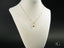 Gold-toned 18k gold necklace featuring a golden heart pendant on a white bust form