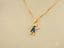 Gold pendant necklace with stick figure charm and blue crystal inlay, Golden Love Pendant
