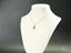 Delicate 18k gold Golden Love Pendant displayed on white jewelry bust