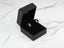 Gold and ruby teddy bear earrings in a black jewelry box beside 18k gold ladybug stud earrings