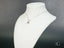 Silver necklace with round pendant on white jewelry bust showcasing 18k white gold design