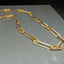 Luxury 18k gold zirconia necklace with alternating gold and sparkling links displayed on a dark background.