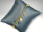 18k gold charm bracelet with nautical elegance and sea-inspired pendants on gray cushion