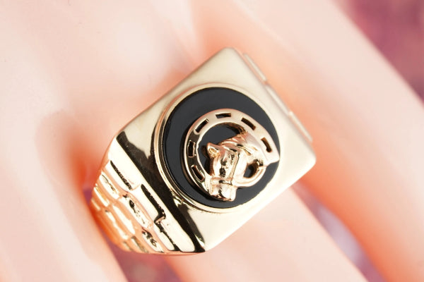 Gold signet ring with black enamel face featuring a raised gold jaguar head, onix horse shoes motif