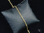 Gold chain necklace on dark gray cushion showcasing 18k solid gold elegance