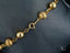 Gold bead bracelet featuring smooth and textured spheres with a spring ring clasp
