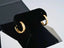 Pair of 18k yellow gold hoop earrings on a black jewelry stand for stylish elegance