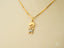 Gold pendant necklace featuring a stylized figure charm from the Timeless Charm collection