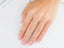 Delicate silver ring on a woman’s finger with pink nails, showcasing 18k yellow gold elegance