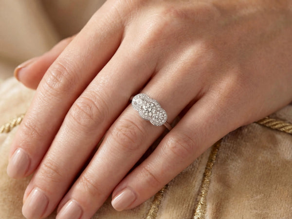 Angled top view of white gold three-stone diamond ring with halo design
