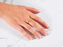 Womans hand with French-tipped nails wearing Blossom Charm 18k gold ring with diamond centerpiece