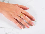 Womans hand with French-tipped nails wearing Blossom Charm 18k gold ring with diamond centerpiece