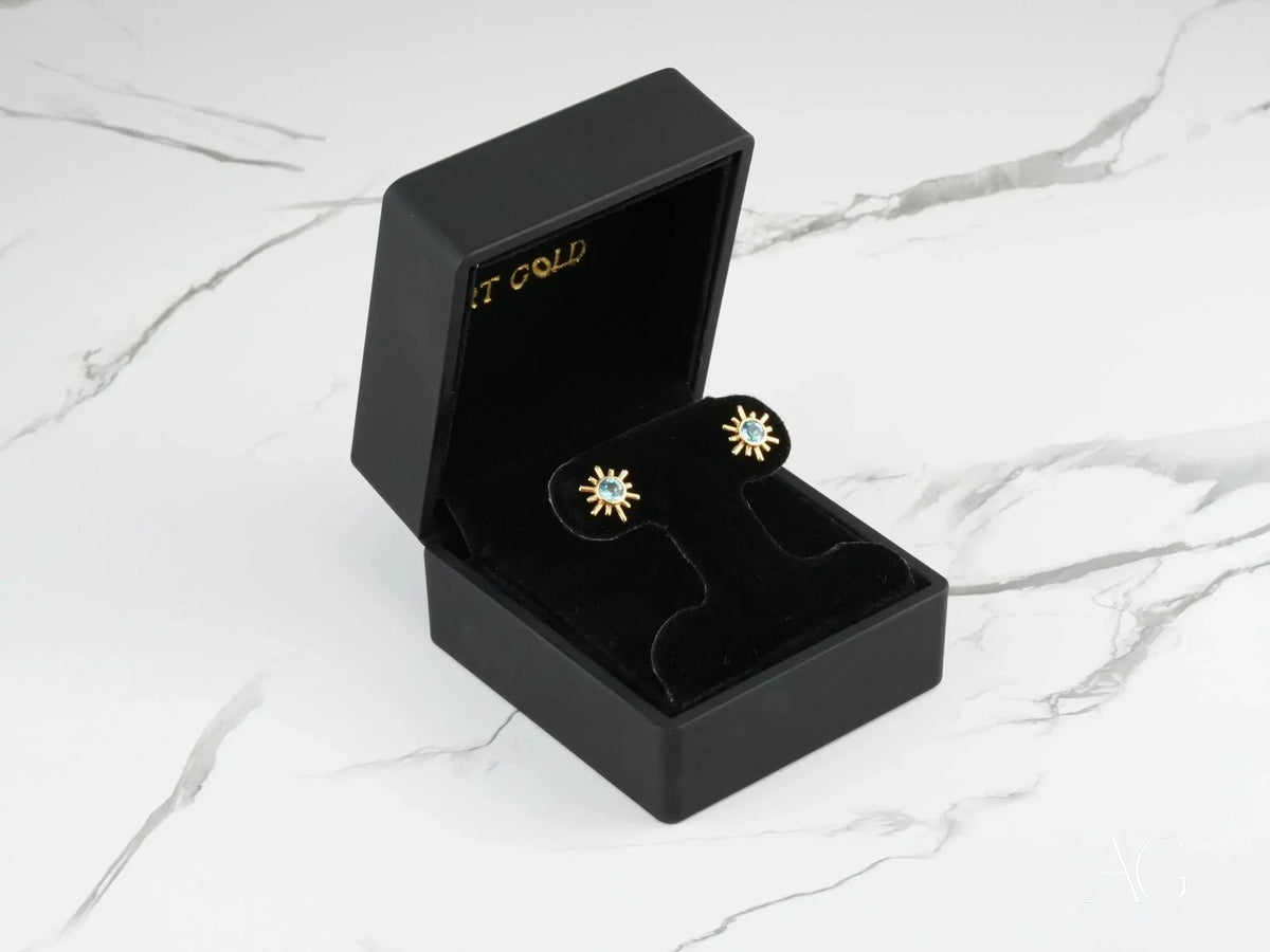 Open Celestial Glow 18k gold blue topaz stud earrings in black box