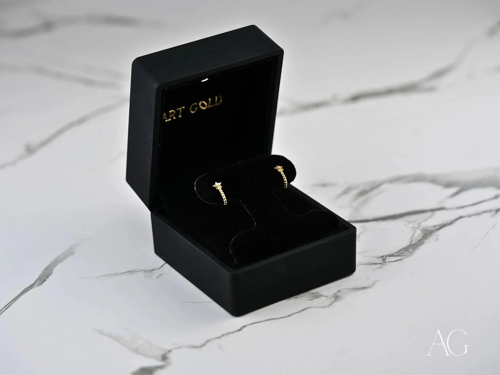 Black velvet box displays Celestial Glow 18k gold star earrings