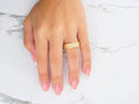 Womans hand with pink white French tip nails wearing Celestial Path wedding band in art gold jewelry