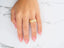Woman’s hand with pink and white French-tipped nails wearing Celestial Path wedding band in art gold jewelry