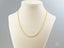 Delicate 18K gold chain necklace on cream mannequin