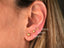 Three 18K gold ball stud earrings of varying sizes on earlobe