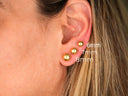 Three 18K gold ball stud earrings of varying sizes on earlobe