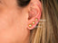Three 18K gold ball stud earrings of varying sizes on earlobe