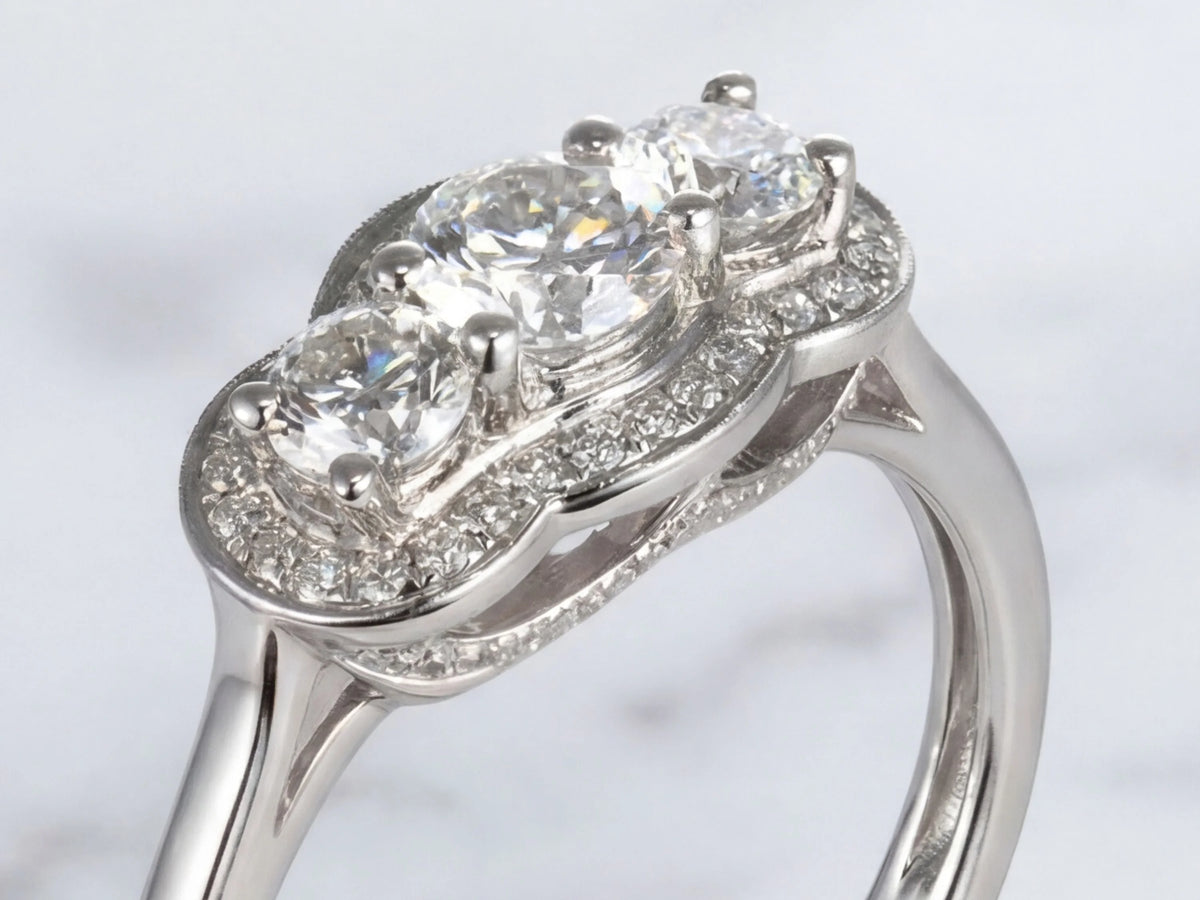 Close-up angled view of white gold three-stone diamond ring with halo details