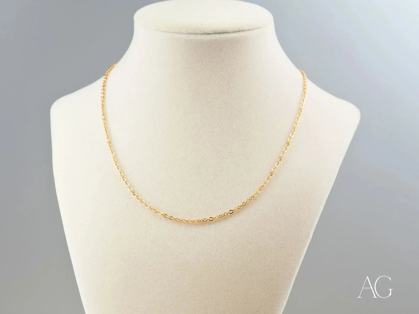 Delicate 18K gold chain necklace on cream mannequin