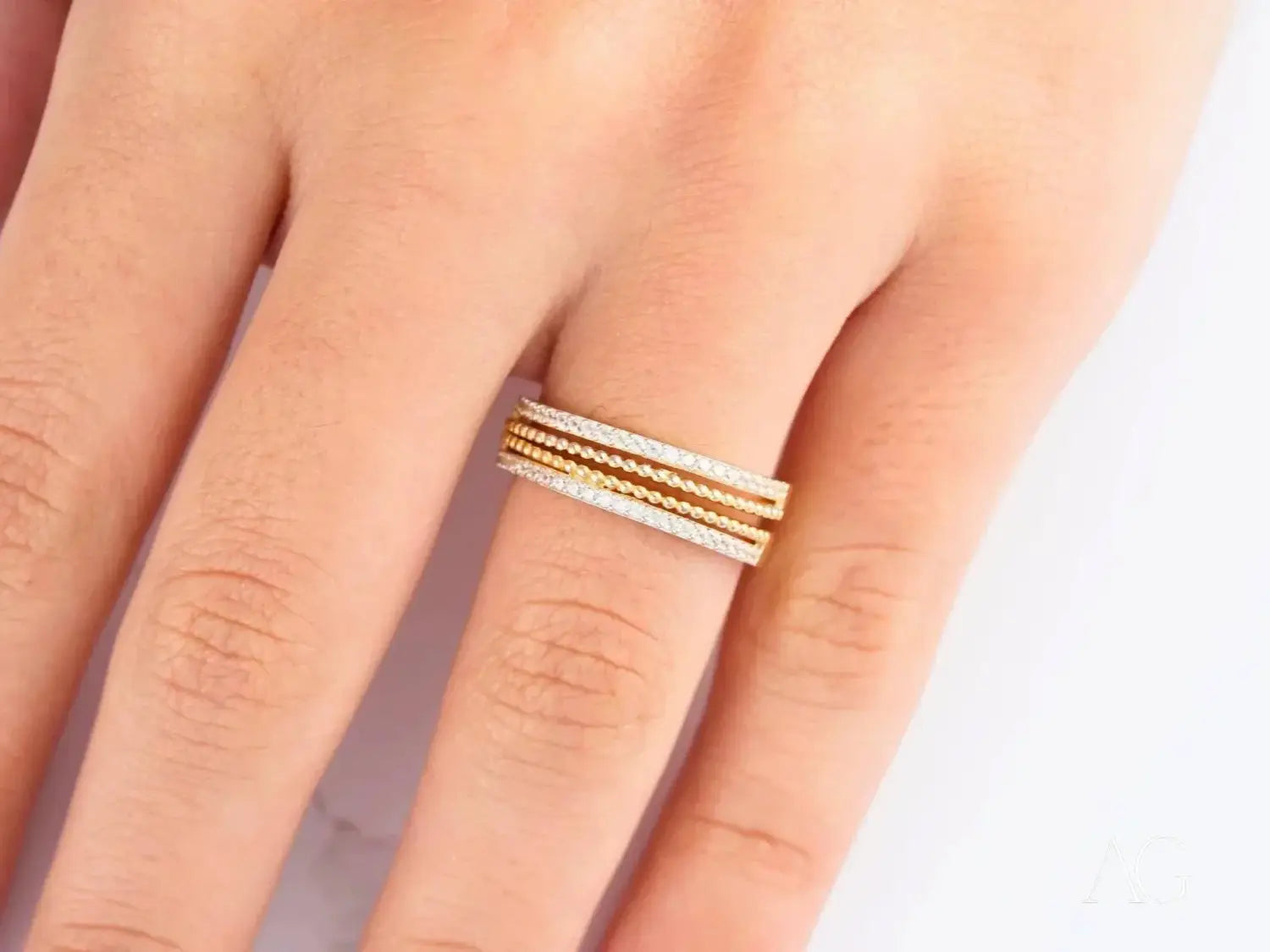 Two interlocking gold rings with beaded design on an ornate silver tray showcasing custom gold fine jewelry.