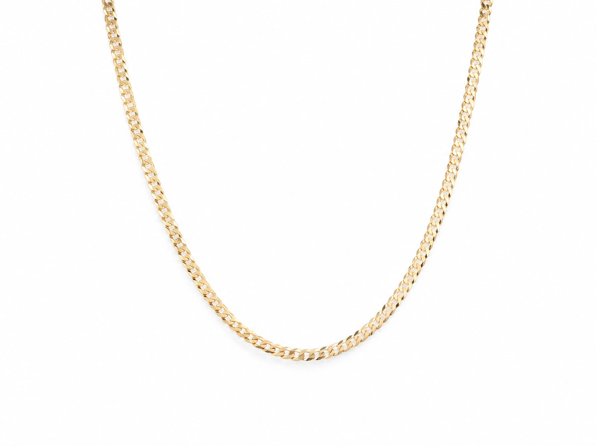 14K yellow gold Cuban chain laid in a U shape on white, flat interlocking curb links