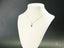 Dual Elegance Pendant in 18k solid gold with red stone on white jewelry display bust
