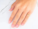 Hand with manicured nails wearing 18k yellow gold CZ heart ring