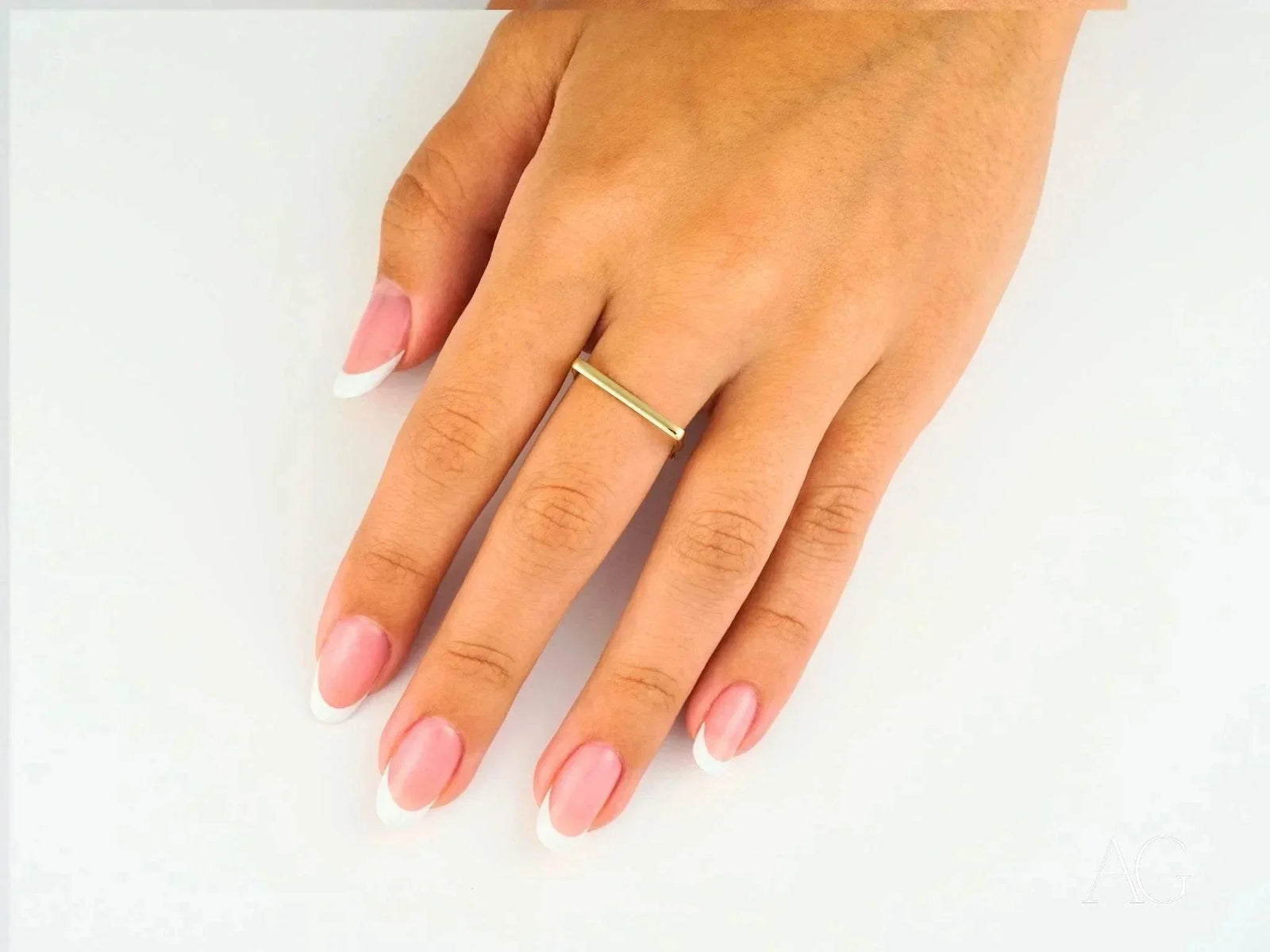 Elegant 18k yellow gold square shape ring on woman’s hand with French manicure