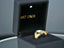 Open black jewelry box with illuminated 14k gold initial letter ring featuring a gemstone