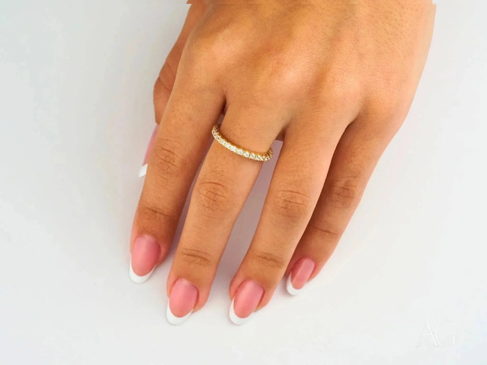 Elegant 18k gold eternity band with sparkling cubic zirconia on French manicured hand