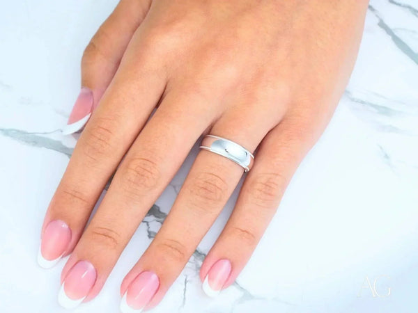 Elegant white 18k gold wedding band on hand with French-tipped nails