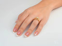 Elegant hand with French-tipped nails cradling 18k gold light engagement ring