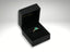 Black velvet ring box with an 18K gold emerald ring featuring a carat radiant-cut emerald