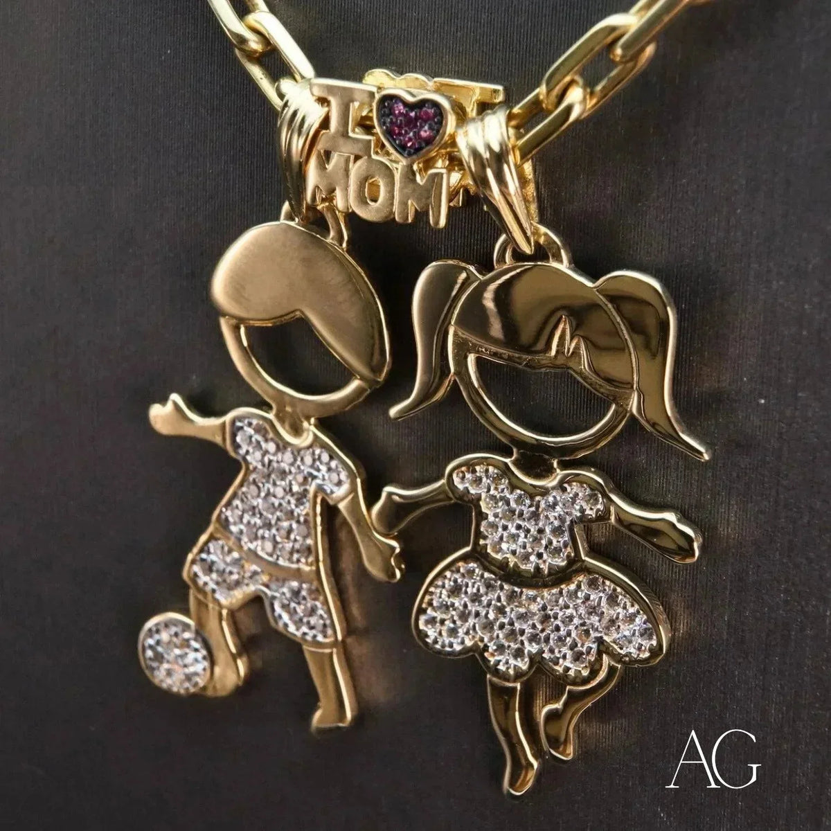 Enchanting 18K gold Boy and Girl doll pendants with CZ beside an I Love Mom charm