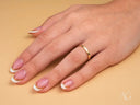 Essence Linea 2mm ring on woman’s hand with French-tip manicure and gold accent