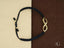 Black braided cord bracelet with a stunning 18k gold infinity symbol charm featuring diamonds
